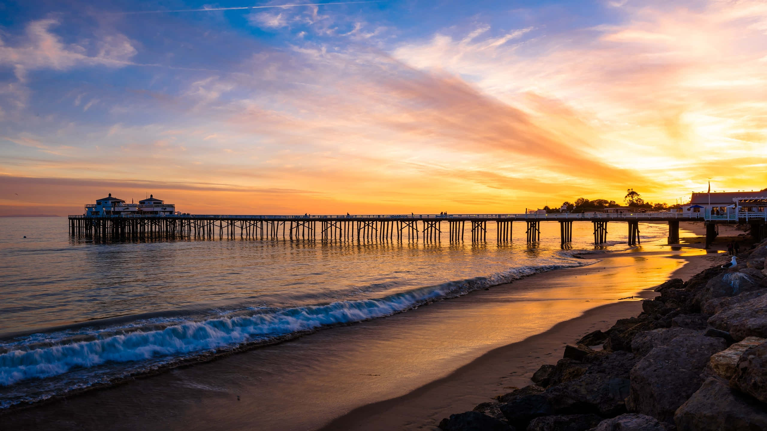 خلفية غروب الشمس الذهبي على رصيف ماليبو بدقة 1440p خلفية
