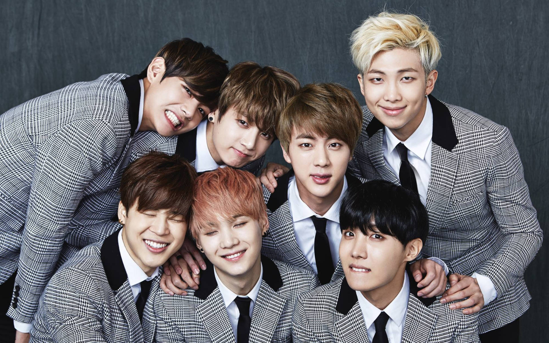 صورة جماعية لفرقة BTS ببدلات رمادية خلفية