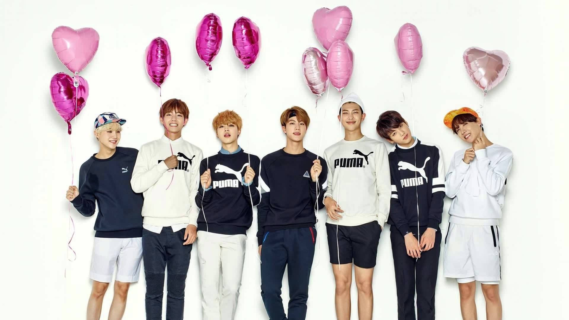BTS يبتسمون ويحملون بالوناً على شكل قلب خلفية