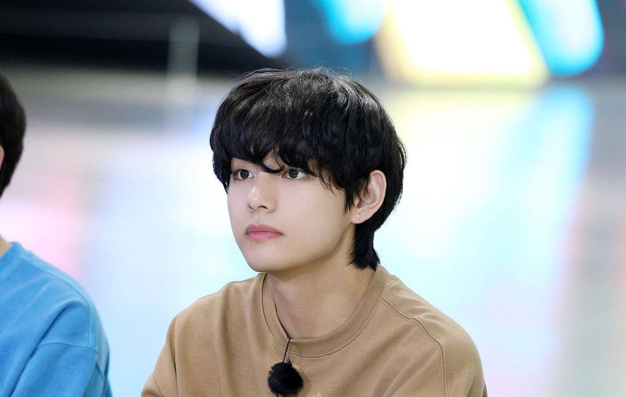 V من BTS بقميص بني خلفية