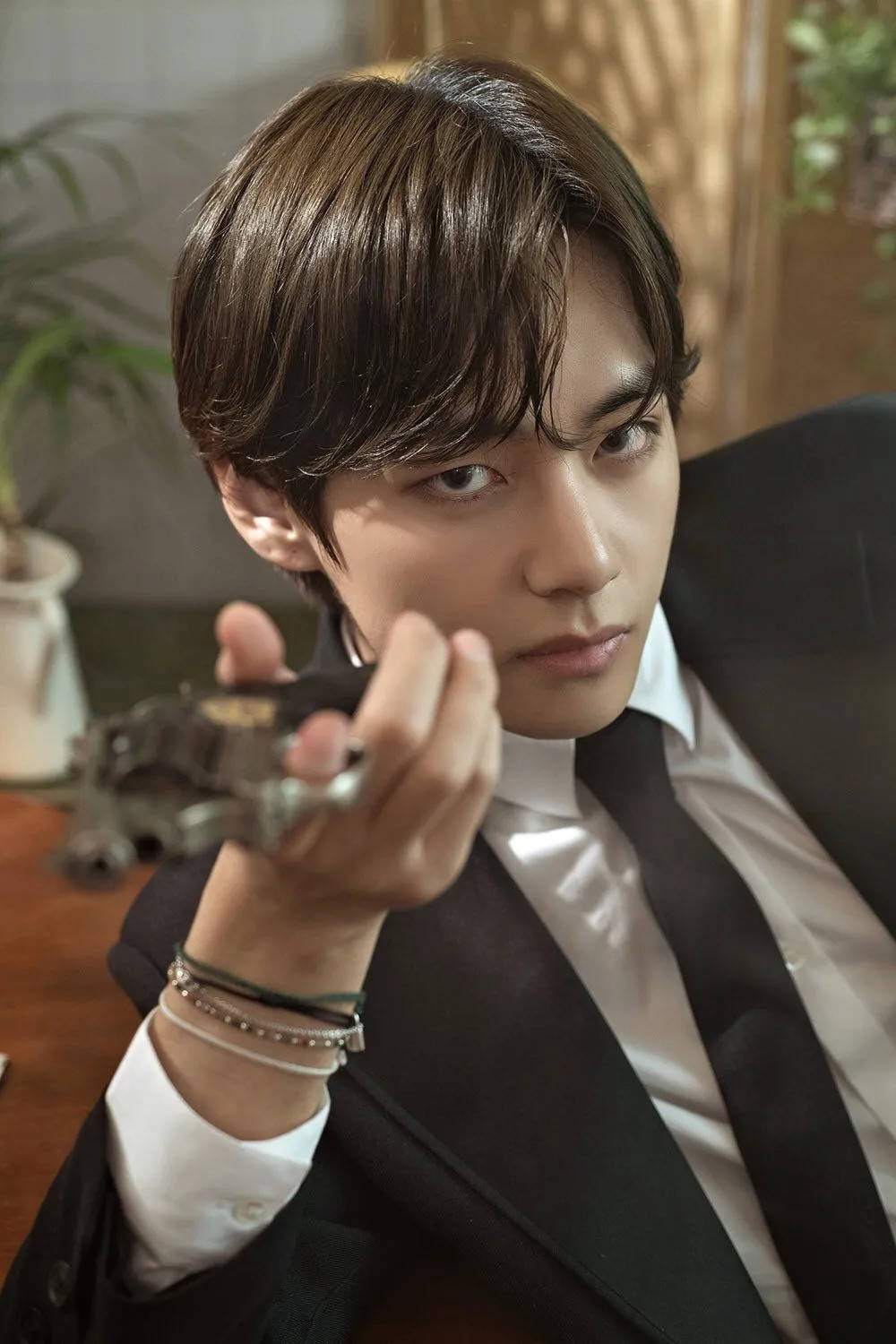 V من BTS يحمل مسدسًا خلفية