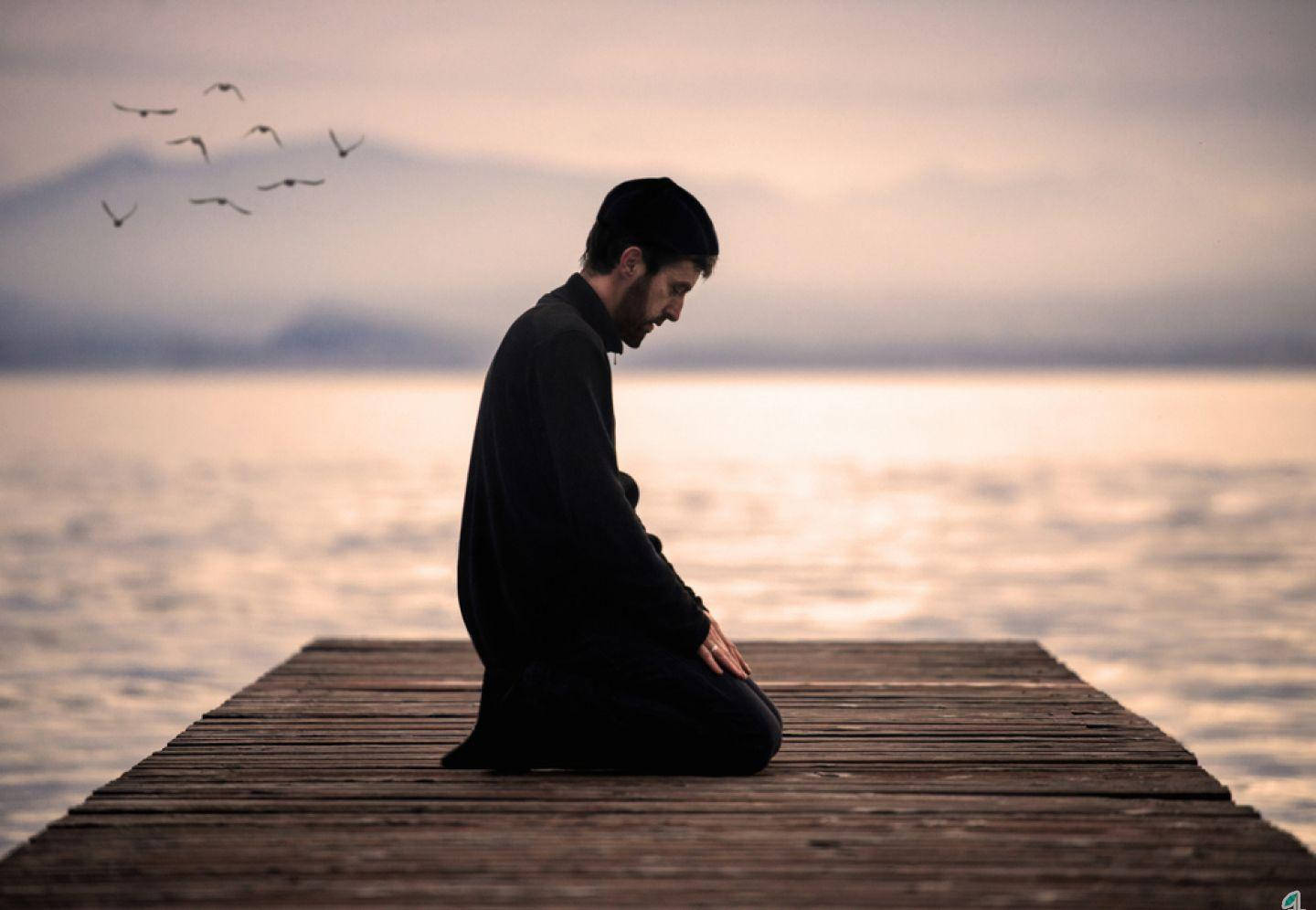رجل يصلي راكعاً على الرصيف خلفية