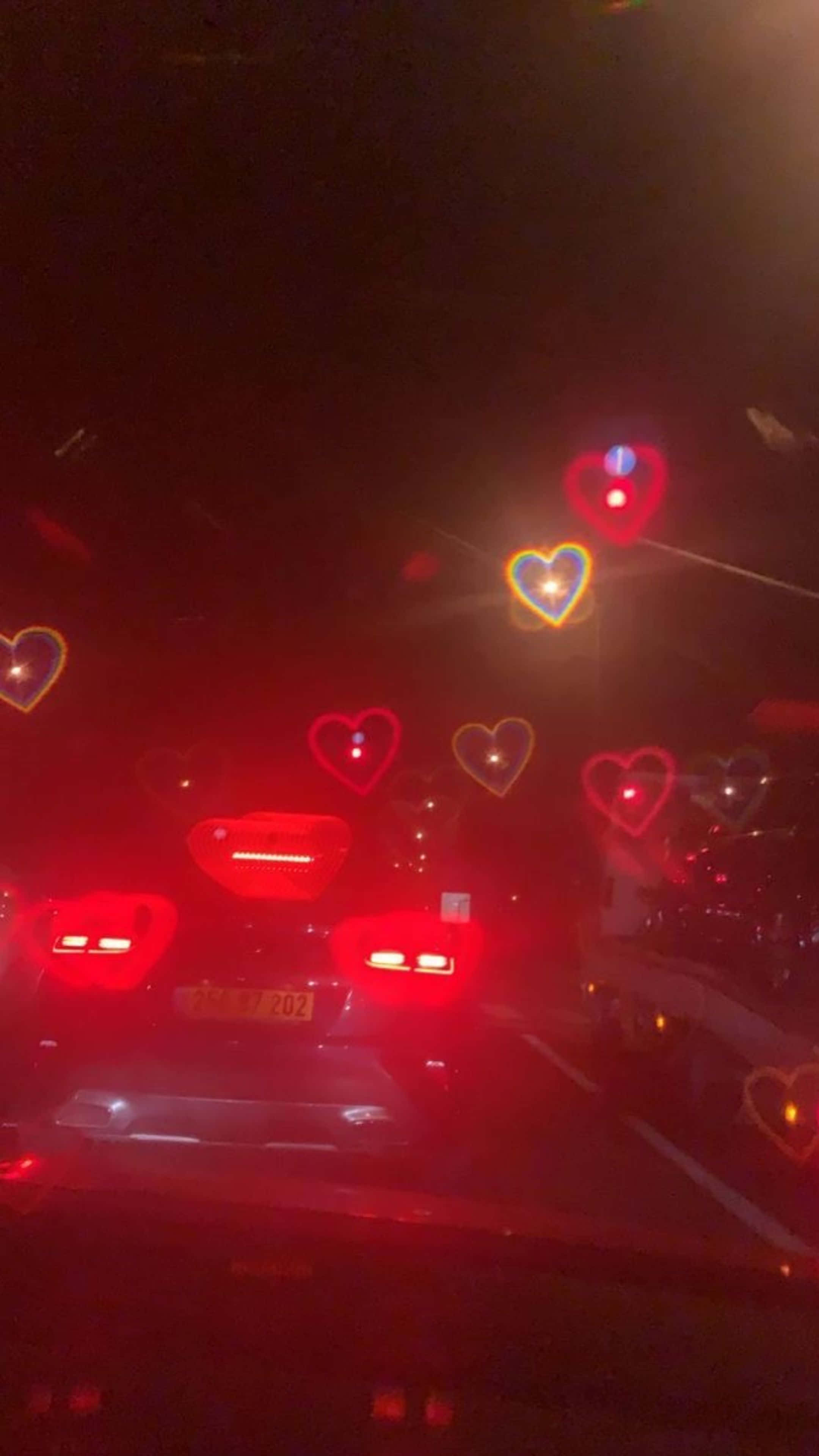 سيارة تسير على الطريق ليلاً مع قلوب على الزجاج الأمامي خلفية