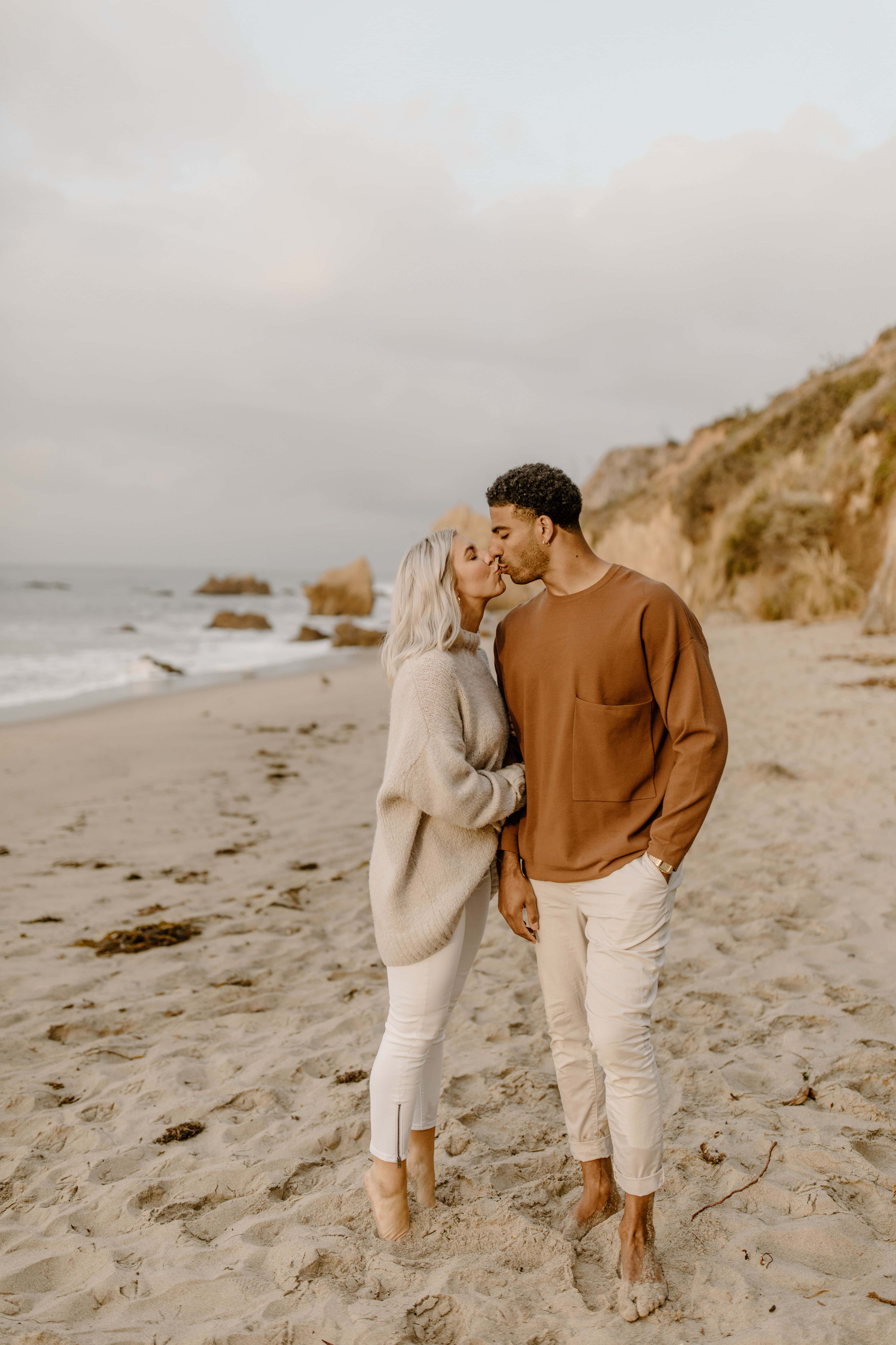 صورة خطوبة لزوجين يقبلان على الشاطئ خلفية