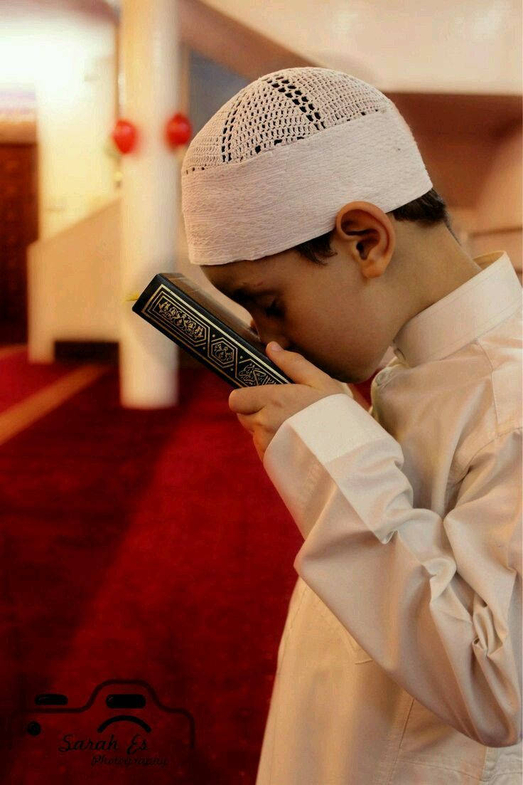 طفل مسلم يقبل القرآن خلفية