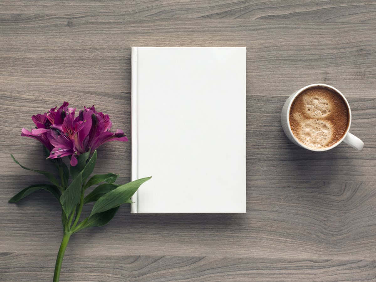 كتاب أبيض وفنجان قهوة على طاولة خشبية خلفية